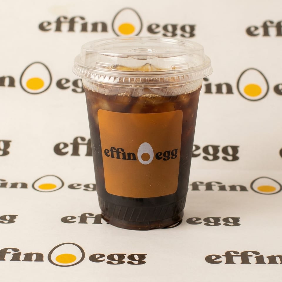 Iced coffee in a clear plastic cup with an "Effin Egg" label, on a branded background.