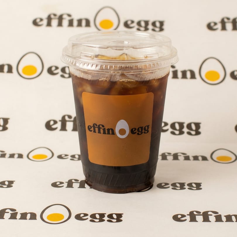 Iced coffee in a clear plastic cup with an "Effin Egg" label, on a branded background.