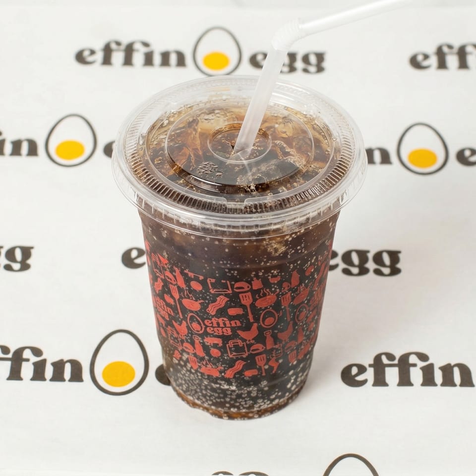 A cold soda in a branded Effin Egg cup with a straw, on a white background.