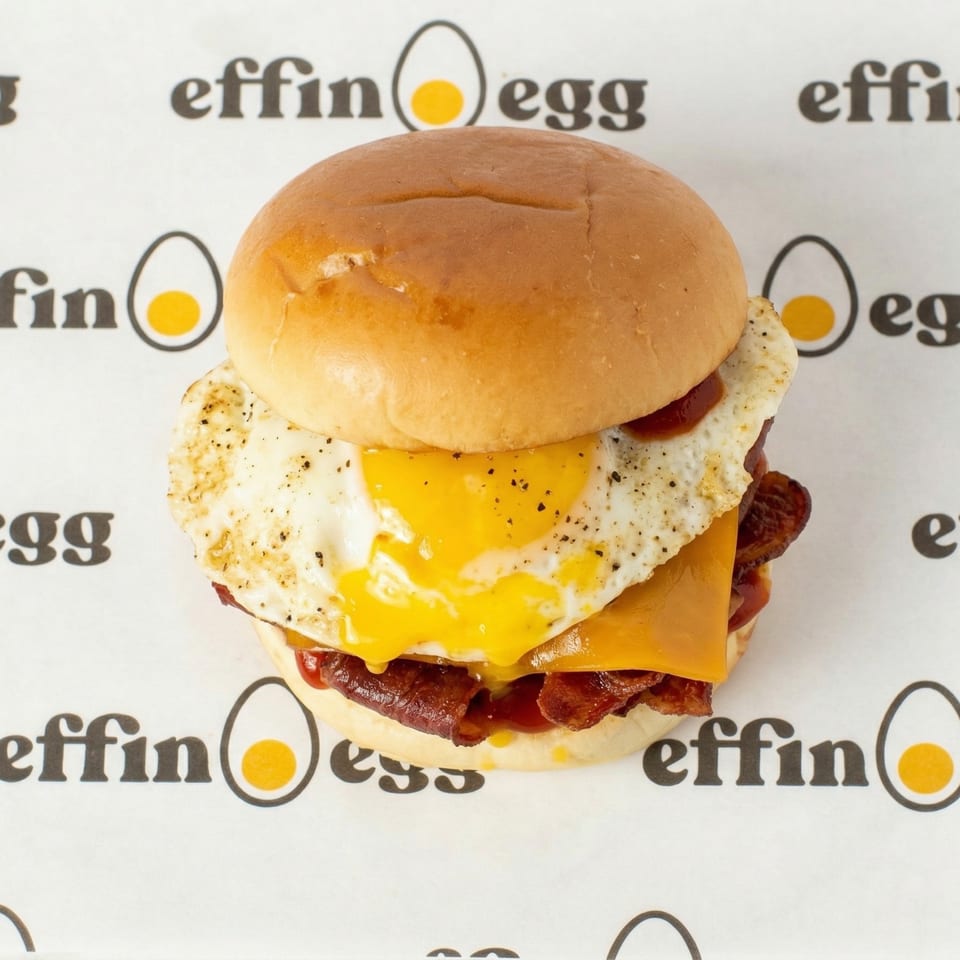 An Effin' Egg breakfast sandwich with bacon, cheese, and a fried egg with runny yolk.